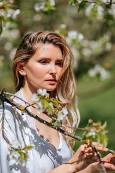 Portrait of a blonde in the park. Beautiful woman with long blond hair in a blue dress