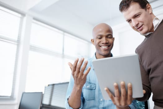 This technology makes life so easy. Two business colleagues sharing a digital tablet in the office