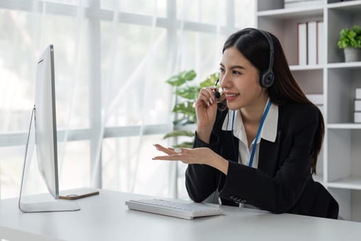 female operator working on computer and while talking with clients. Concept relevant to both call centers and customer service offices.