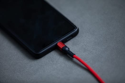 Charging the battery of a cell phone by connecting it with a wire to an electric charger.