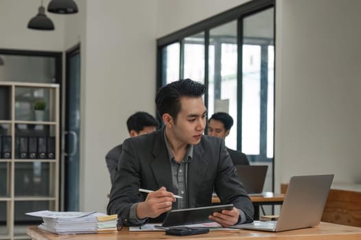 business man sitting in office and working on laptop and tablet.