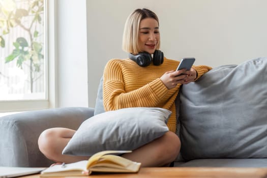 Happy asian woman pretty girl relaxing at home, resting, typing on smartphone, using online app, software, shopping on Internet, making video call. Mobile phone communication.