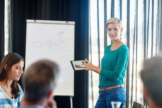 Presenting the future. an attractive woman showing her colleagues graphs on a digital tablet during her presentation