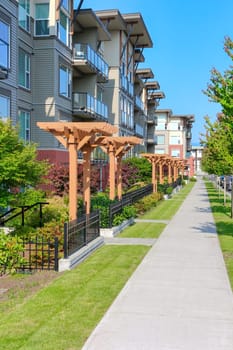 Paved walkway along the residential building with private entrnaces on a bright sunny day.
