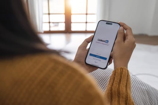 CHIANGMAI, THAILAND - MAY 1, 2023 : A women holds Apple iPhone 14 with LinkedIn application on the screen.LinkedIn is a photo-sharing app for smartphones...