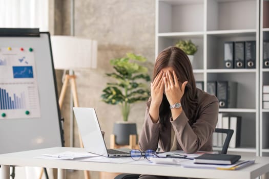 Young Asian businesswoman working on laptop computer, stressed has a headache and thinks hard from work at the office...