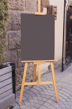 Wooden blackboard in front of restaurant entrance. Mock up menu blank board sign stand near shop or cafe restaurant. Street sidewalk chalkboard.