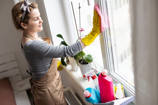 Woman cleaning and polishing the kitchen worktop with a spray detergent, housekeeping and hygiene concept