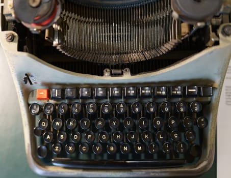 Close-up view from above of an old and worn-out typewriter with lateral lighting.