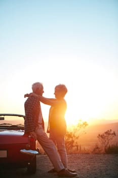 Making romance an important part of their lives. an affectionate senior couple enjoying the sunset during a roadtrip