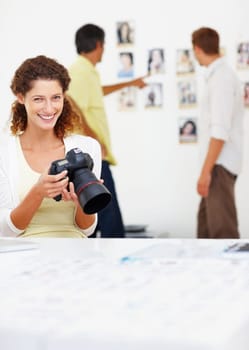 Smiling female photographer viewing images in camera. Portrait of smiling female photographer viewing images in camera with colleagues in background