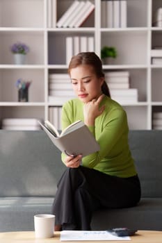 Attractive Asian woman resting comfortable living room and reading book, Relax, Sofa, Lifestyle.