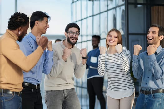 Group of happy managers rejoice at a successful deal by clenching their hands into fists and raising them up