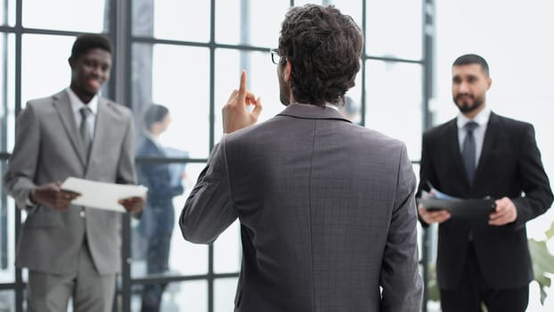 a man stands with his back against the background of his colleagues in the office