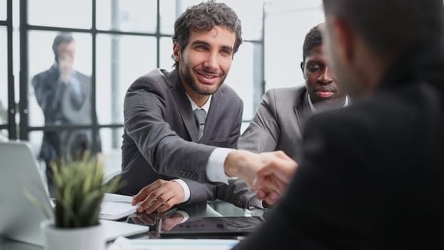 Sealing a deal. Top three men sitting at the desk and shaking hands