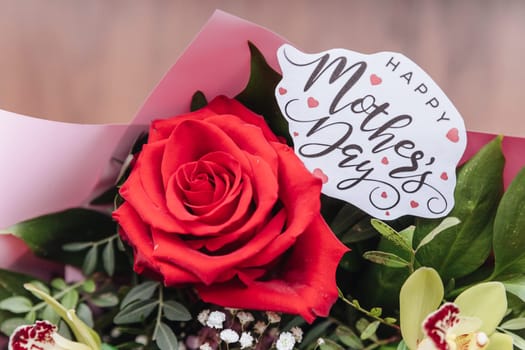Happy Mothers Day text on gift card with flower bouquet of roses, tulips, eucalyptus on purple background.