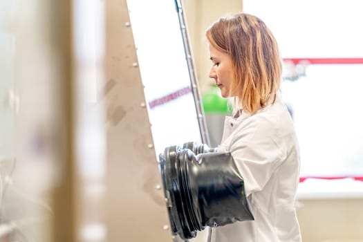 a scientist in protective rubber gloves conducts research in a vacuum chamber in a laboratory. High quality photo