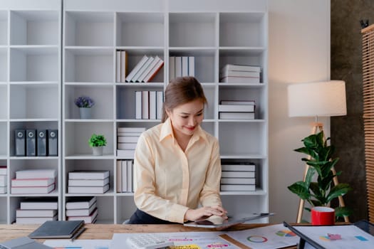 businesswoman in a black suit inside the office using tablet computer, audit paperwork for customers to contact, business people concept