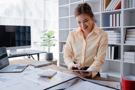 businesswoman in a black suit inside the office using tablet computer, audit paperwork for customers to contact, business people concept