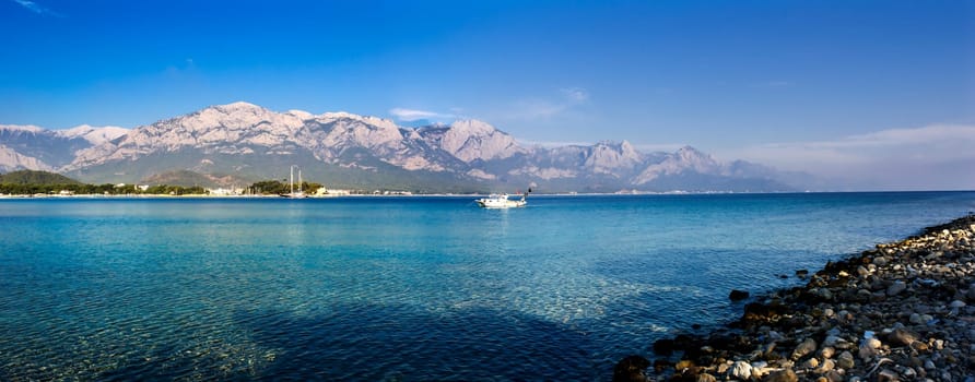 Kemer Antalia nice view of the sea. Beach Kemer Antalia with sand and mountains, the sea with the ship. Beautiful harbor near the sandy beach.