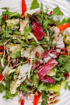 Fresh salad of cabbage, herbs, peppers, carrots and pomegranate seeds in a white plate. High quality photo