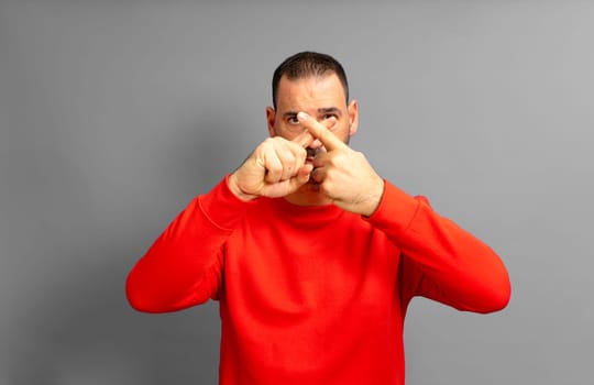 Hispanic man with a beard in his 40s making a stop gesture crossing his index fingers, isolated over gray background