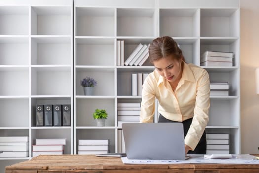 Excited business asian woman sitting at table with laptop and celebrating success..