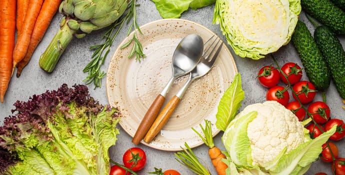 Assorted food raw products: vegetables, beef meat, fish salmon and empty plate in centre, dark rustic brown stone table top view copy space. Healthy food background, ingredients for balanced diet