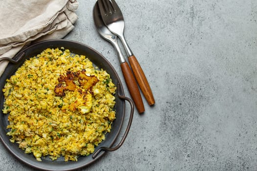 Fried cauliflower rice or couscous with dill on plate, healthy low carbohydrates vegetable side dish for keto diet and healthy low calories nutrition on rustic stone background, space for text