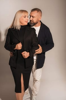 A man and a woman in strict clothes pose against the background in the studio.