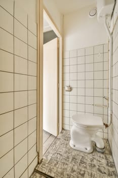 a bathroom with white tiles on the floor and walls, including a toilet in the middle part of the room