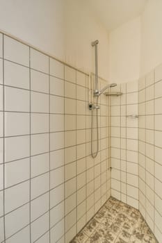 a bathroom with tile on the floor and shower head mounted to the wall, in front of white tiled walls