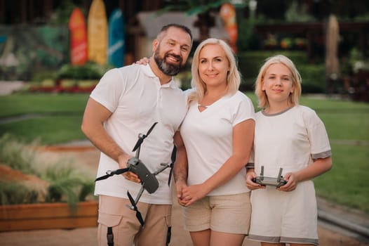 The family is hugging and holding a quadcopter and a remote control in their hands.