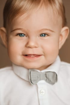 Portrait of a cheerful little boy in a white shirt with a bow tie.