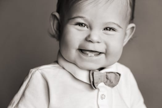 Portrait of a cheerful little boy in a white shirt with a bow tie.