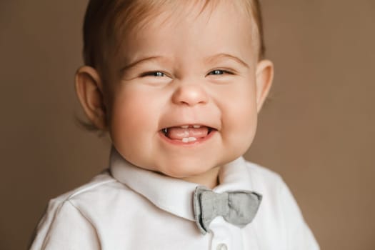 Portrait of a cheerful little boy in a white shirt with a bow tie.