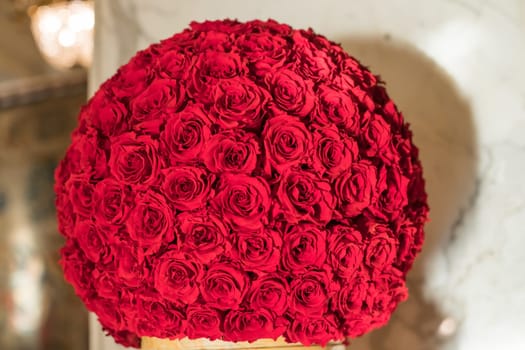 A decorative ball of red rose sepals stands on a white surface in the interior. Soft focus.