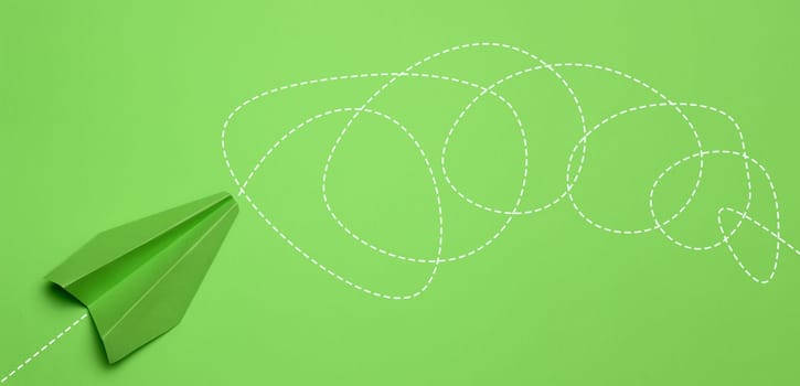A green paper airplane on a green background with a long and convoluted path drawn, representing the concept of confusion, perplexity, and the difficulty of the journey