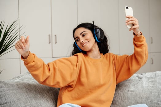 A young beautiful Arab woman has chosen her favorite playlist and dances to the music. The girl listens to her favorite song through headphones enjoys her day off.