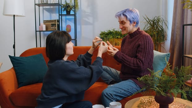 Two lesbian women family couple. Homosexual female girl gay making a surprise engagement ring love proposal of marriage to her beloved woman. Accepting emotionally say yes. LGBT people at home room