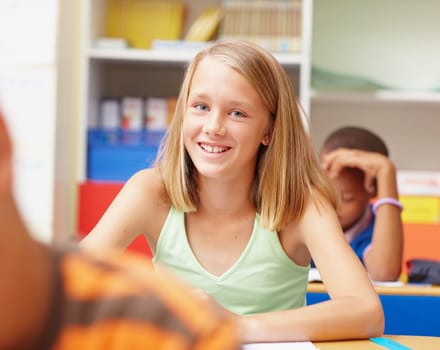 First-rate education for outstanding individuals. Confident young elementary school girl sitting at her desk in class smiling at you