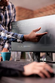 Enginners discussing about coding script compiling discovers errors, standing in front of multiple screens in startup office. Diverse programmers working on server interface development.