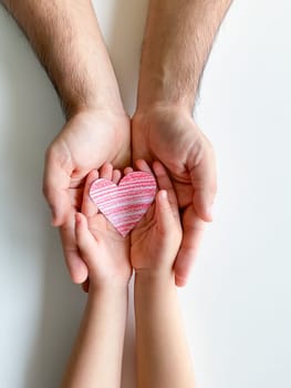 adult and childrens hands hold a small red paper heart. Fathers Day. Family, love, parents, children, care, tenderness