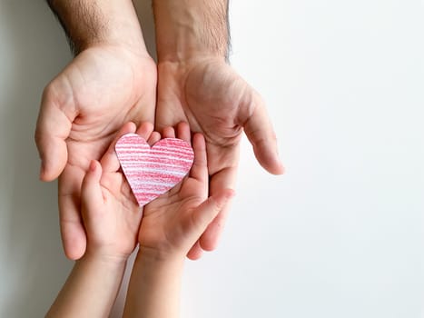 adult and childrens hands hold a small red paper heart. Fathers Day. Family, love, parents, children, care, tenderness