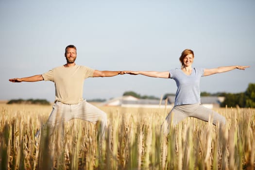 Living a healthy lifestyle together. Portrait of a mature couple enjoying a yoga workout in a crop field