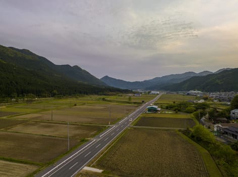 Open road through rural Japanese village in mountain valley at sunset. High quality photo