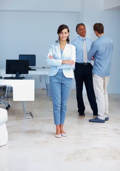 Business woman with staff discussing. Full length of young business woman standing with colleagues conversing in background