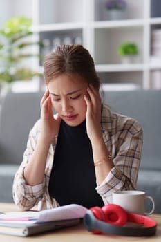 Stressed woman sits on sofa at home, studying and analyze house bills and submitting tax forms..