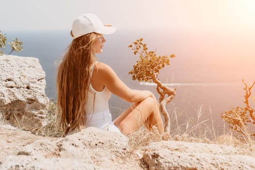 Woman travel sea. Young Happy woman in a long red dress posing on a beach near the sea on background of volcanic rocks, like in Iceland, sharing travel adventure journey