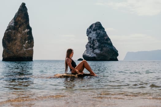 Woman travel sea. Young Happy woman in a long red dress posing on a beach near the sea on background of volcanic rocks, like in Iceland, sharing travel adventure journey